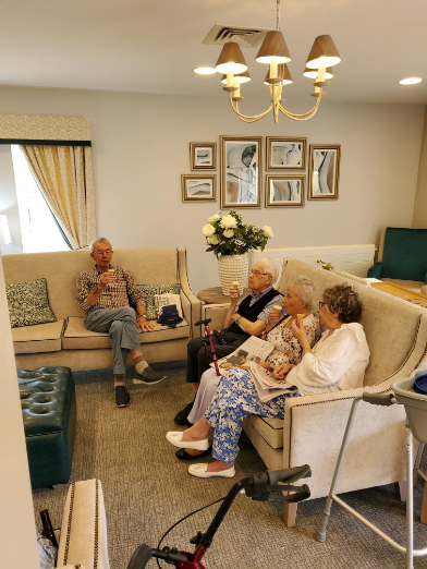 A male resident and three female residents sat in the lunge eating ice cream cones chatting.