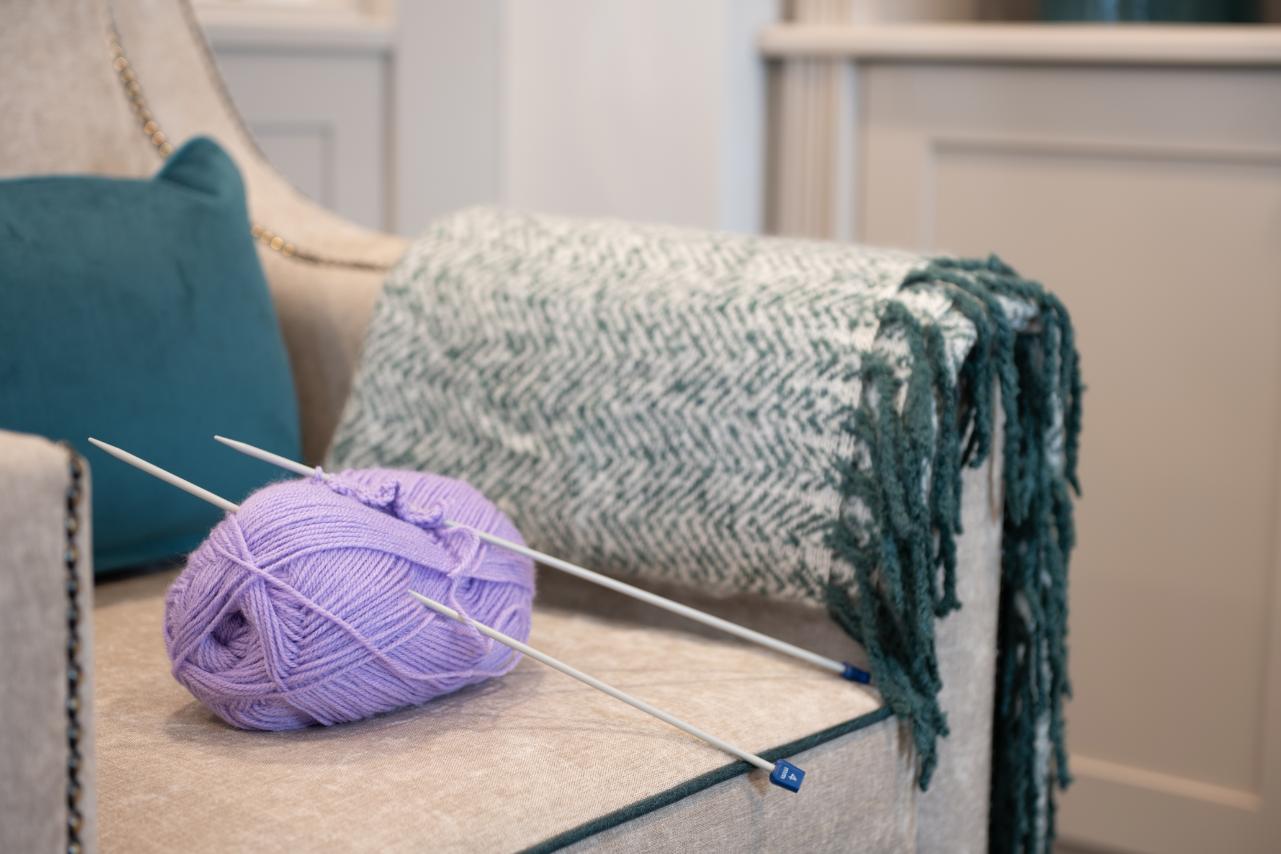 purple yarn and knitting needles on an armchair