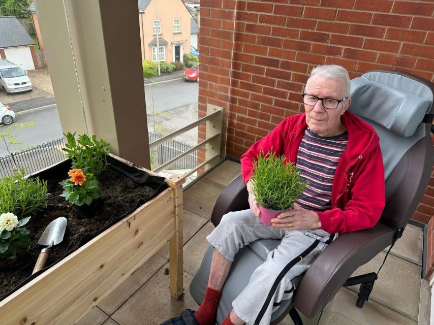 older man in a wheelchair holding a plant pot